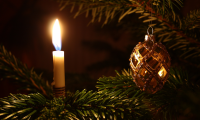 Brændende lys og julekugle på grangren