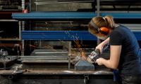 Kvinde med høreværn på udfører metalarbejde